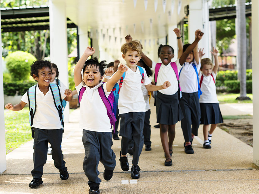 Group of children wearing backpacks and running and cheering