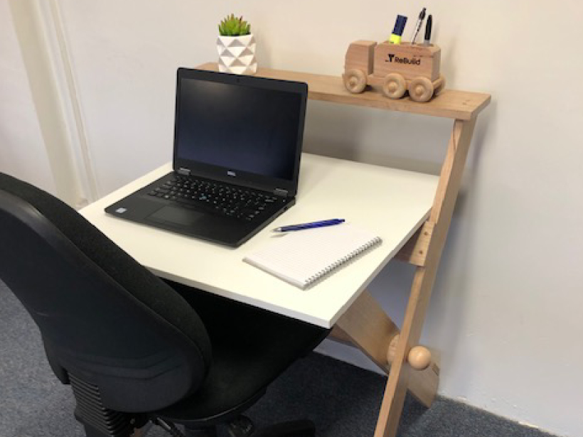 Folding desk standing up against the wall with desk items on it.